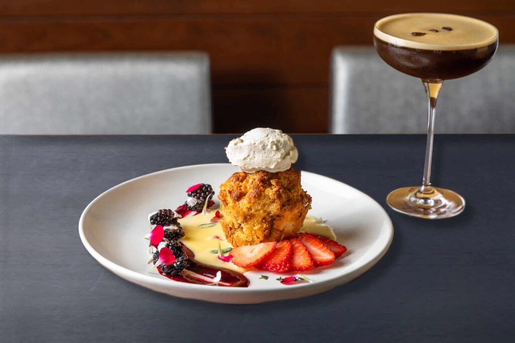 Plate of bread pudding with berries, accompanied by an espresso martini