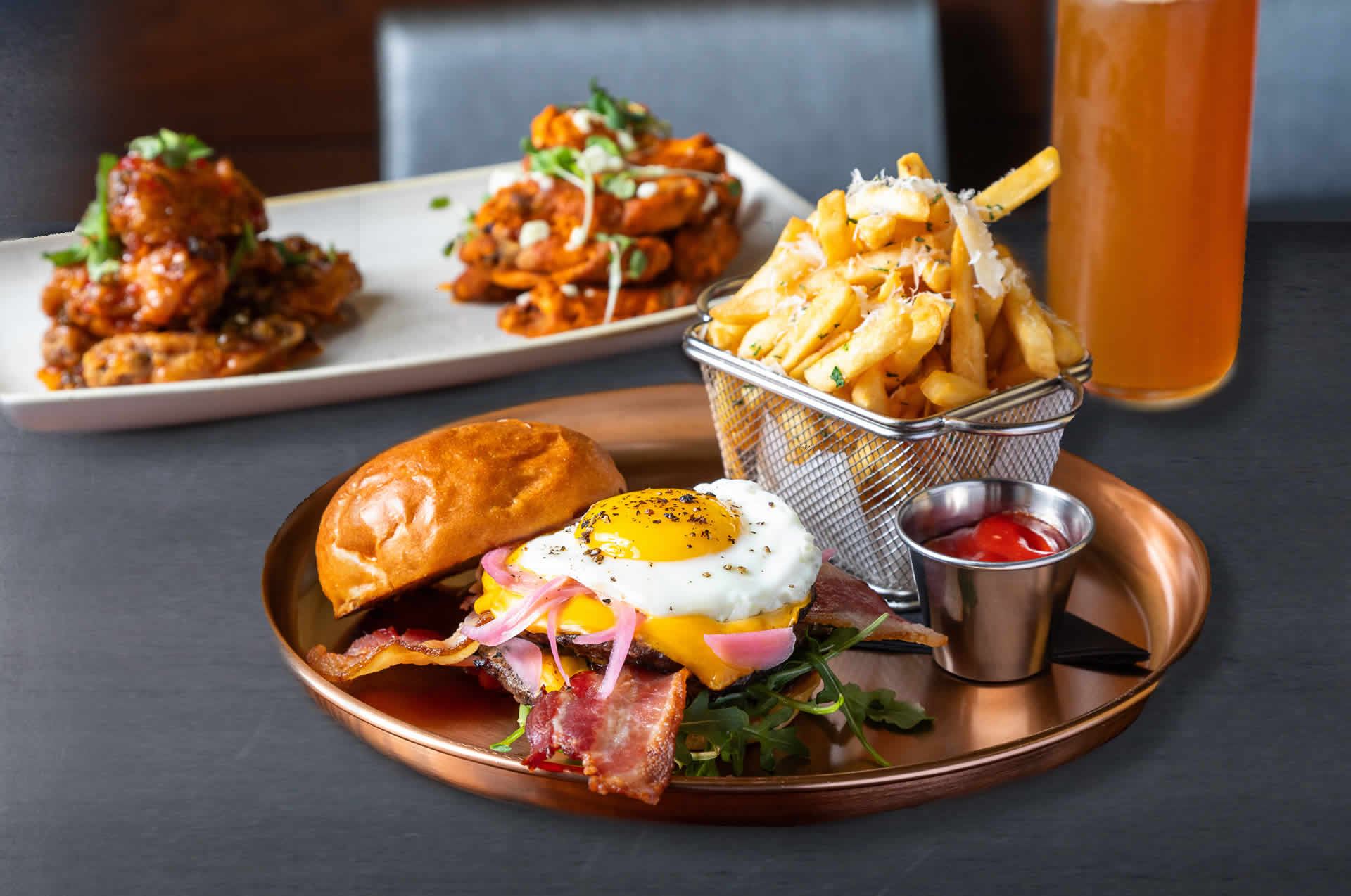 Hamburger with sunny-side up egg, french fries, and buffalo wings