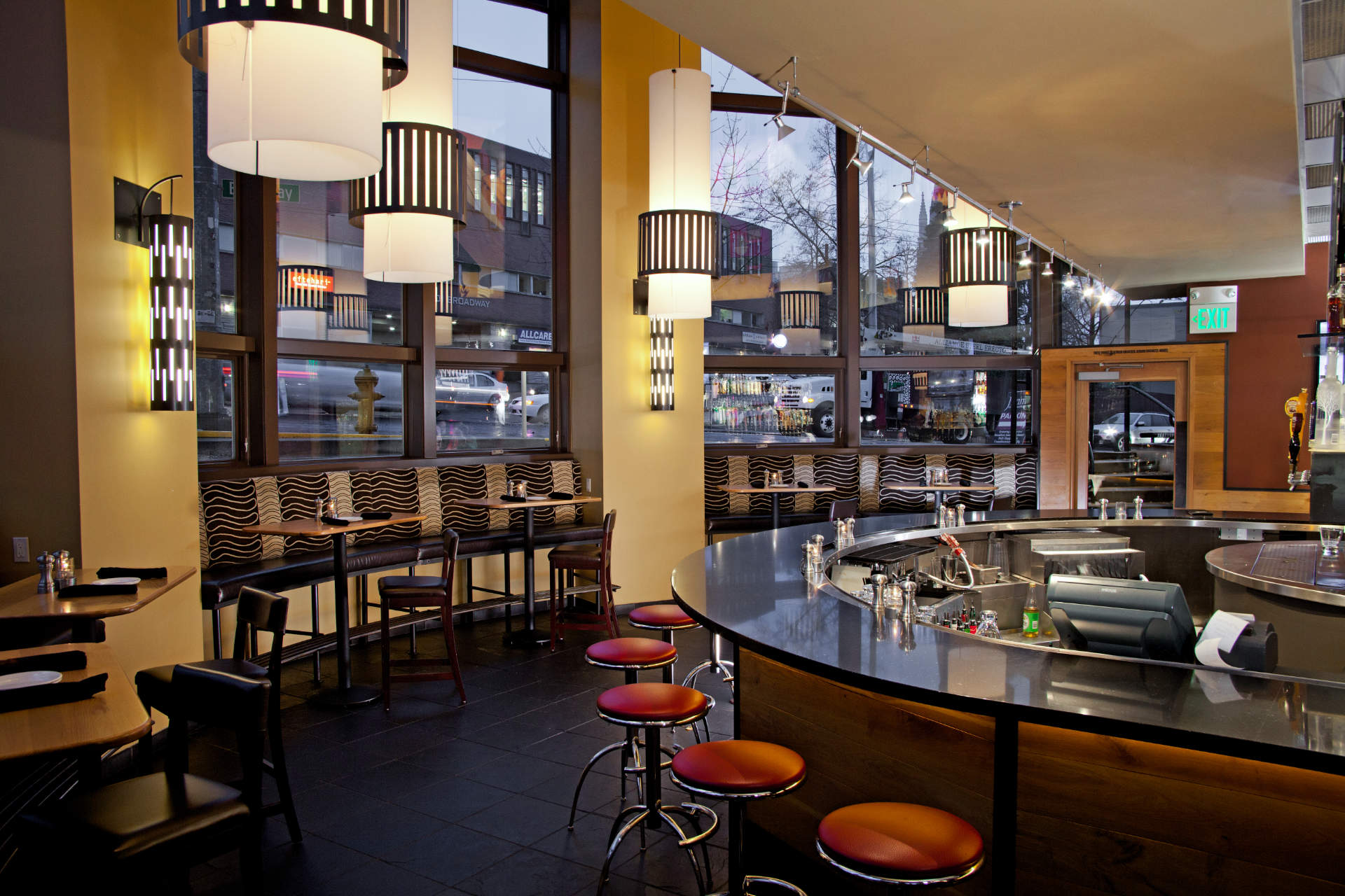 Dining room and circular bar with red stools and yellow walls at Jimmy's on Broadway