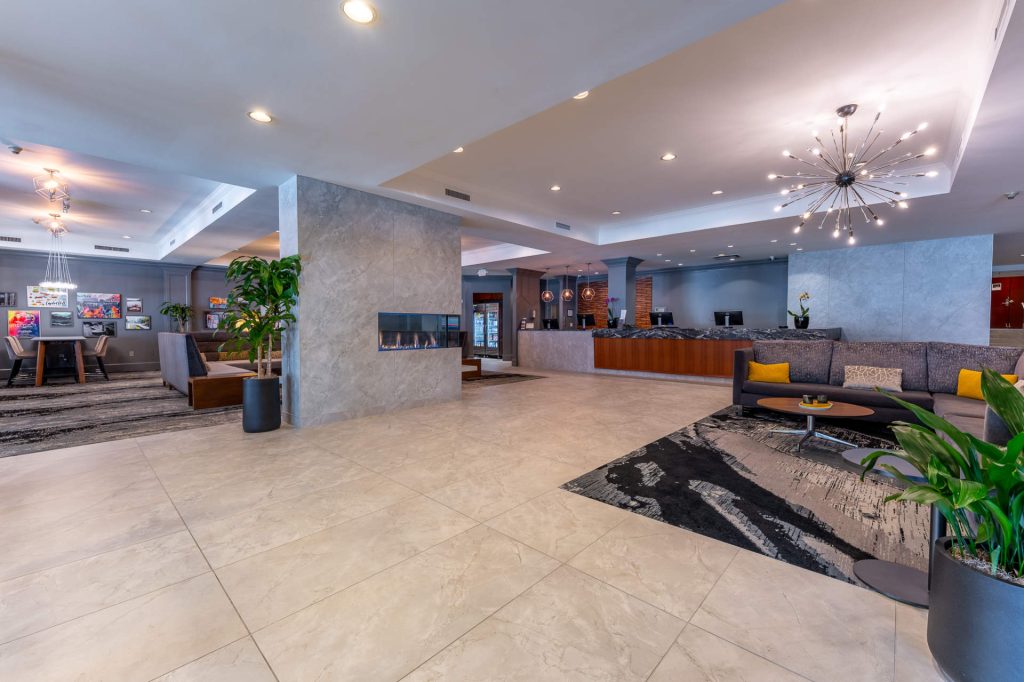Hotel lobby with front desk, lounge seating and a modern fireplace